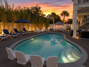 A swimming pool with lounge chairs and a dining area, surrounded by trees and a sunset. - 5-Bedroom steps from the Gulf and Alys Beach (Seacrest)