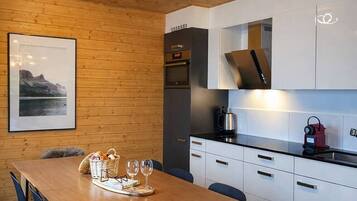 A modern kitchen with white cabinets, a wooden dining table, and a black chair with a fur throw.