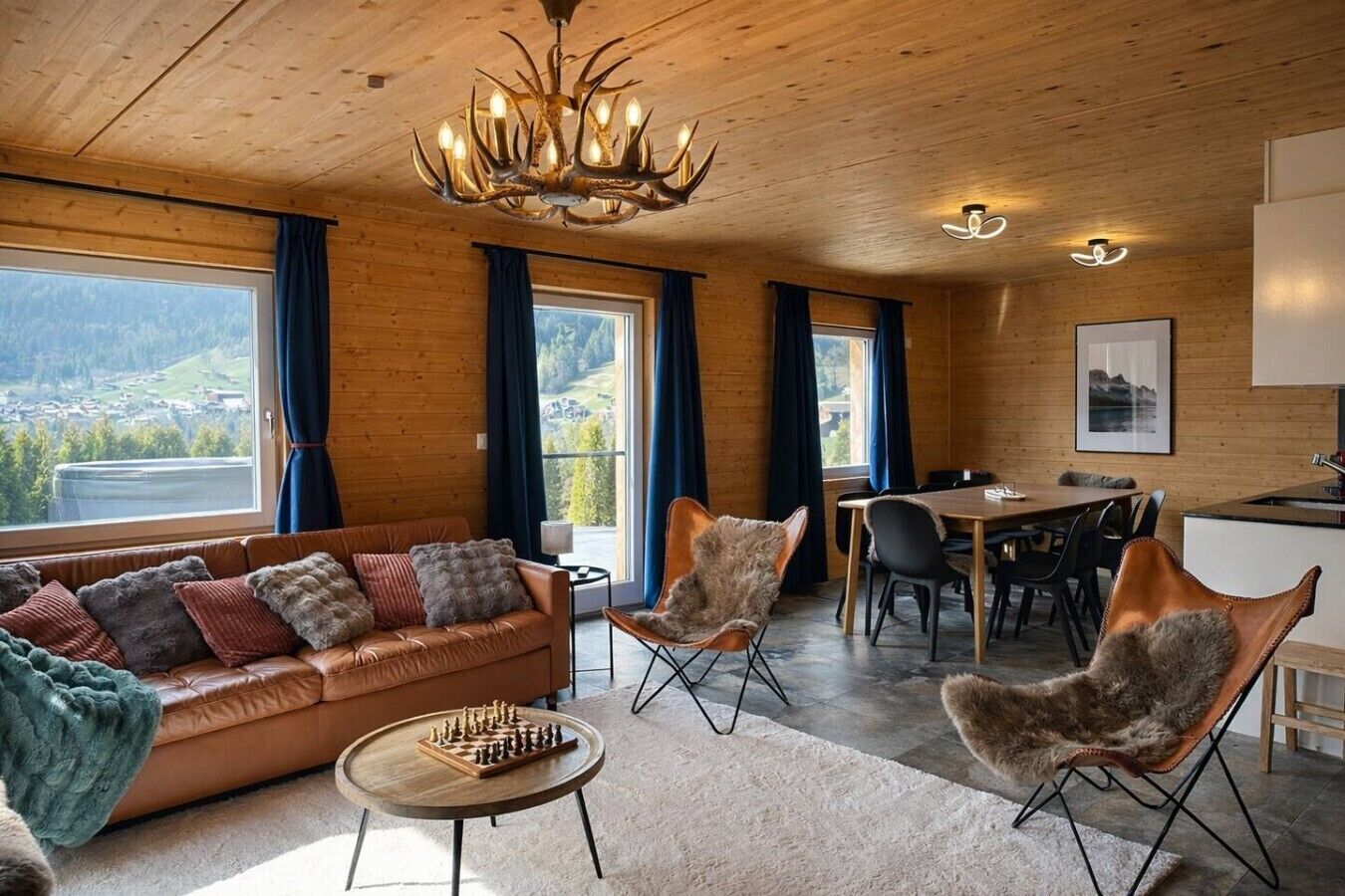 Un salon chaleureux avec un canapé en cuir, un lustre et une vue sur l’extérieur.