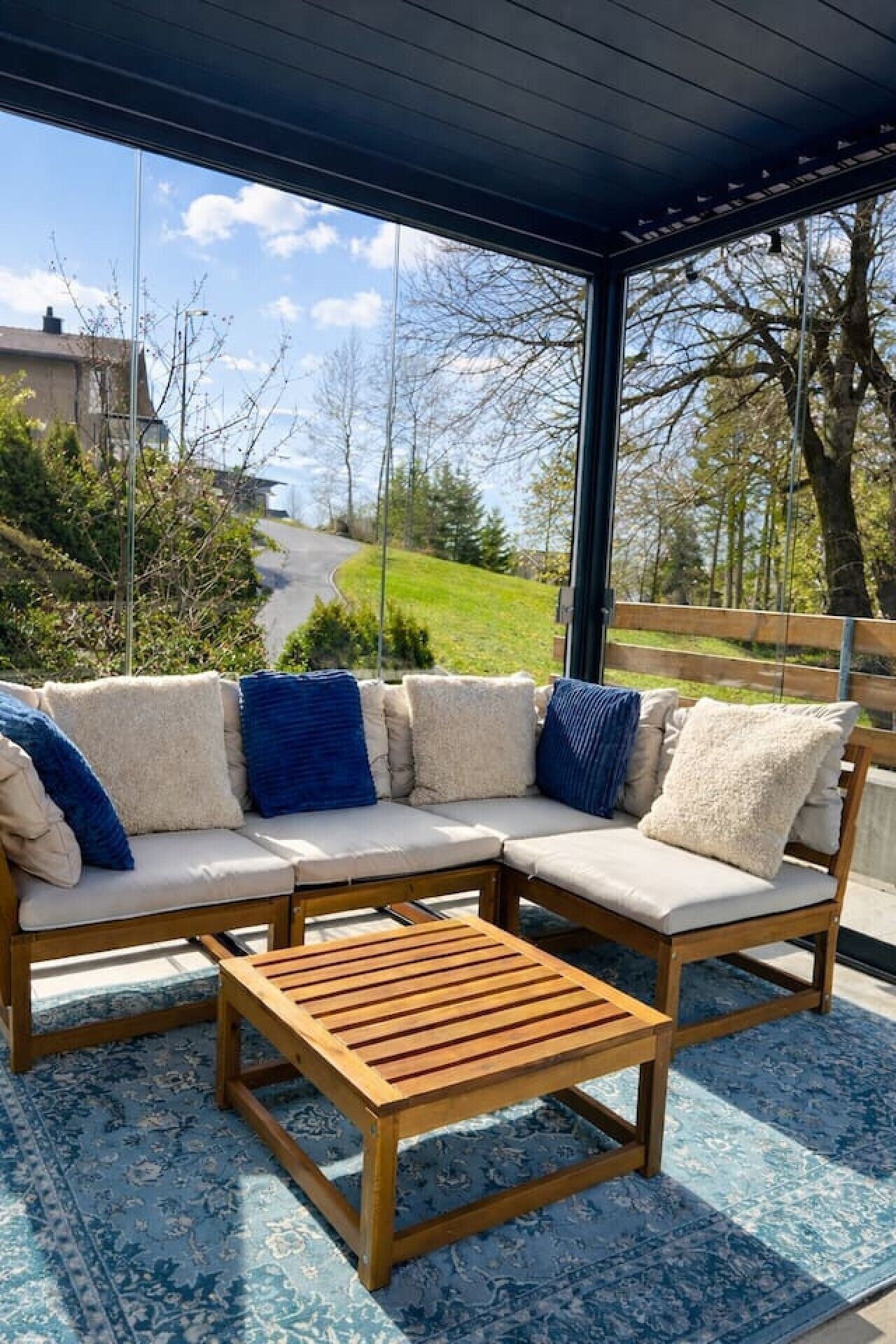 A covered outdoor seating area with a wooden table and cushioned chairs.