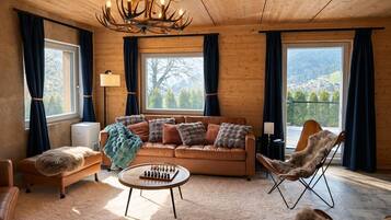 A cozy living room with a sofa, a chair, a chess table, and a chandelier.