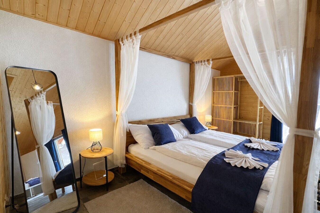 Een slaapkamer met een bed, nachtkastje met lamp, spiegel en kledingkast.