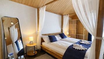 Een slaapkamer met een bed, nachtkastje met lamp, spiegel en kledingkast.
