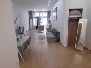 A modern living room with a dining area, a sofa, a TV, and a wardrobe. - Grilo Apartment (Málaga)