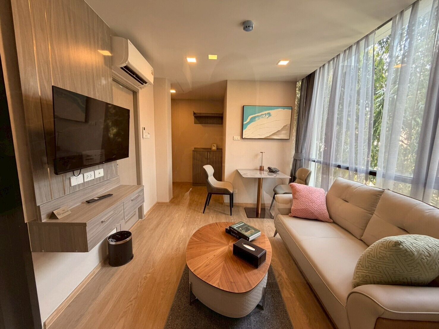 A modern living room with a flat-screen TV, a sofa, a coffee table, and a dining area.