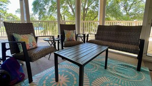 A covered outdoor seating area with wicker furniture, a wooden table, and a patterned rug. - Pelican’s Perch: 3 minute walk to the beach, shops, restaurants and pavilion. (North Myrtle Beach)