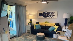 A living room with a sofa, ottoman, and a ceiling fan. - Pelican’s Perch: 3 minute walk to the beach, shops, restaurants and pavilion. (North Myrtle Beach)