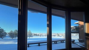 A room with large windows offering a view of a snowy landscape and a distant building.