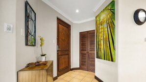 A hallway with a wooden door, a wall-mounted mirror, a painting, and a tiled floor. - Reserva Conchal Escape With Golf Course Views (Cabo Velas)