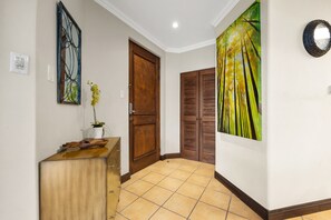 A hallway with a wooden door, a wall-mounted mirror, a painting, and a tiled floor. - Reserva Conchal Escape With Golf Course Views (Cabo Velas)