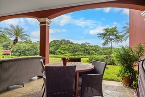 A covered patio with wicker furniture and a view of a lush garden. - Reserva Conchal Escape With Golf Course Views (Cabo Velas)