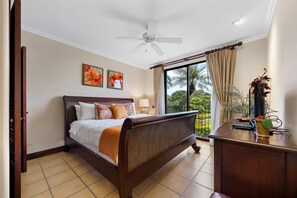 A bedroom with a bed, a desk, a ceiling fan, and a view of the outdoors. - Reserva Conchal Escape With Golf Course Views (Cabo Velas)