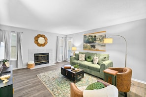 A living room with a fireplace, a green sofa, a coffee table, and a lamp.