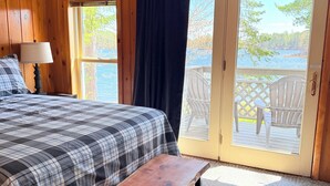 Ein Schlafzimmer mit Bett, einer Bank, einem Deckenventilator und Blick auf eine Terrasse und einen See.