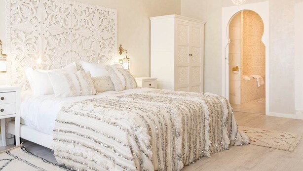 Une chambre à coucher avec un grand lit, une tête de lit décorative, une armoire et un lustre.
