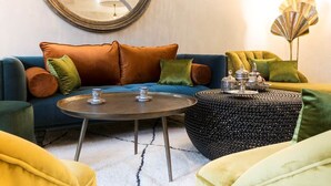 Un salon avec un canapé bleu, une table basse ronde et une lampe décorative.