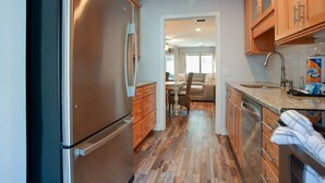A kitchen with wooden cabinets, stainless steel appliances, and a dining area with a sofa and table. - Relax & Unwind|2BR Sea Pines Getaway (Hilton Head Island)