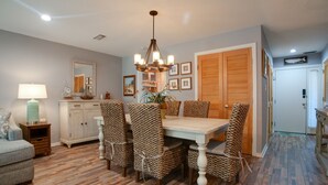 A dining area with a table, chairs, a chandelier, and a cabinet. - Relax & Unwind|2BR Sea Pines Getaway (Hilton Head Island)