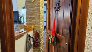 Eine Holztür mit einer roten Weihnachtsdekoration, eine Steinsäule und eine Holzbank mit rotem Kissen.