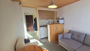 Ett kompakt bostadsutrymme med ett litet kök, en soffa och en matplats.