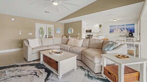 A living room with a sectional sofa, a white coffee table, and a ceiling fan. - Aruba Breeze Retreat | Hot Tub & Pool Table (Fort Myers)
