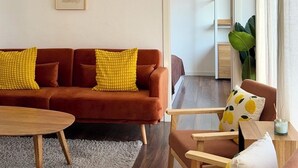 Ein modernes Wohnzimmer mit Sofa, Sesseln, Couchtisch und Essbereich.