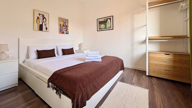 Ein modernes Hotelzimmer mit Bett, Nachttischen, einem Schrank und Kunstwerken an den Wänden.