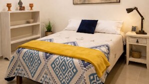 A bedroom with a bed, a ceiling fan, a nightstand, a lamp, a bookshelf, and a wall-mounted painting. - La Hacienda Hotel - Mineral de Pozos (Mineral de Pozos)