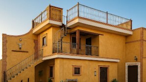 A building with a staircase leading to a balcony, a door, and a bench in the courtyard. - La Hacienda Hotel - Mineral de Pozos (Mineral de Pozos)