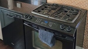 Keittiössä on musta Whirlpool-merkkinen mikroaaltouuni, ruostumattomasta teräksestä valmistettu liesi ja astianpesukone.