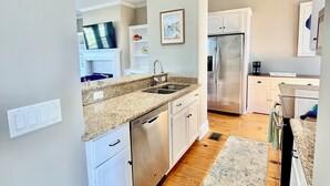 A modern kitchen with white cabinets, granite countertops, stainless steel appliances, and a wooden floor. - 3-bedroom townhome in gorgeous St. Marys with Pool, Boat Ramp and Riverviews (St. Marys)