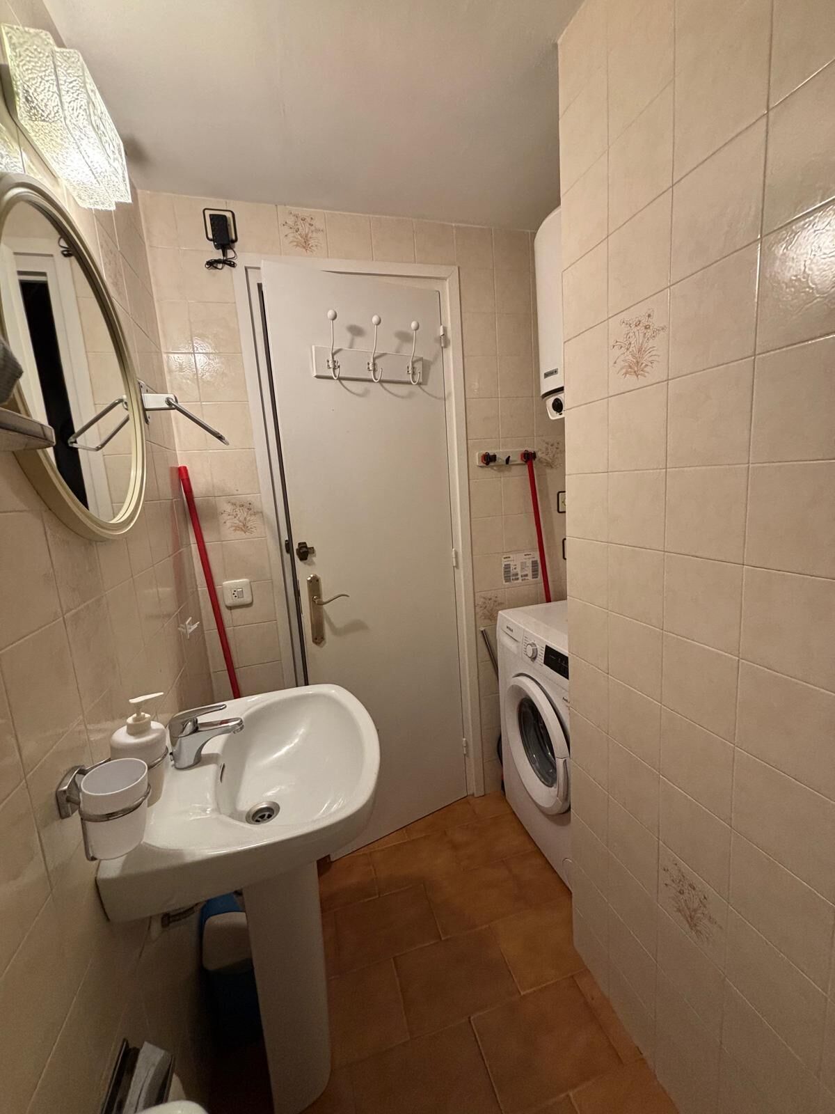 Un baño pequeño con lavabo, espejo y lavadora.