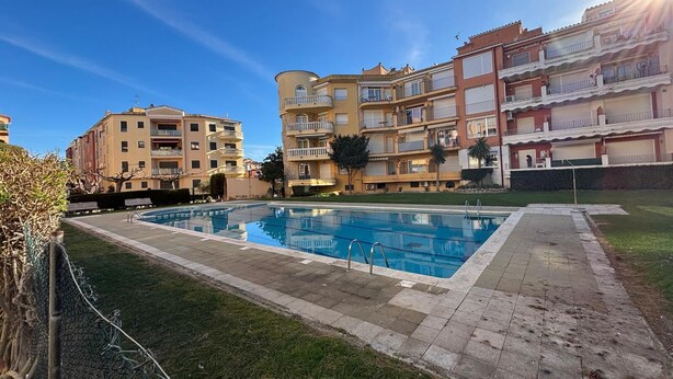A swimming pool surrounded by apartment buildings with balconies, a clear sky, and a sunny day. - Apartment in Empuriabrava 150 meters from the sea, in a residence with 3 swimming pools (Empuriabrava)