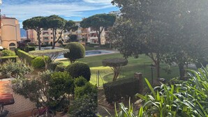 A courtyard with a swimming pool, neatly trimmed hedges, and multi-story buildings in the background. - Apartment in Empuriabrava 150 meters from the sea, in a residence with 3 swimming pools (Empuriabrava)