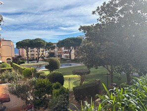 A courtyard with a swimming pool, neatly trimmed hedges, and multi-story buildings in the background. - Apartment in Empuriabrava 150 meters from the sea, in a residence with 3 swimming pools (Empuriabrava)