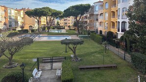 A residential area with a swimming pool, green lawns, and multi-story buildings with balconies. - Apartment in Empuriabrava 150 meters from the sea, in a residence with 3 swimming pools (Empuriabrava)