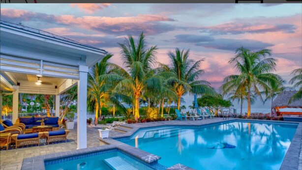 A swimming pool with lounge chairs and palm trees. - Paradise Point -Pet friendly 
Oceanfront Luxury with Pool/ Dock/outdoor kitchen. (Marathon)