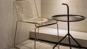 A modern room with a wooden floor, a metal-framed chair, a small round table, and a pendant light. - H Hotel Wangsimni (Seoul)