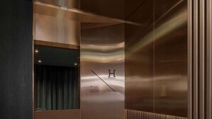 A modern elevator interior with metallic walls and a reflective surface. - H Hotel Wangsimni (Seoul)