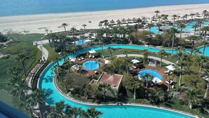 Un resort con varias piscinas, palmeras y vista a la playa.