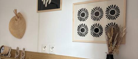 Ein Schlafzimmer mit einem Holz-Kopfteil, einer Uhr, Wandbildern und einer Vase mit getrockneten Blumen.