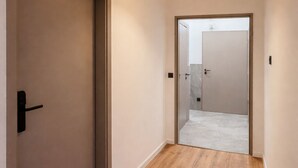 A hallway with wooden flooring, a door on the left, and a bright pendant light. - Privates Vierbettzimmer mit modernem Design (Berlin Sleep Club) (Berlin)