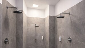 A modern shower area with grey tiles, a rectangular layout, and a ceiling light. - Privates Dreibettzimmer mit modernem Design (Berlin Sleep Club) (Berlin)