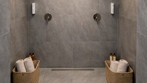 A modern bathroom with two showerheads, a ceiling light, and two baskets with towels. - Privates Dreibettzimmer mit modernem Design (Berlin Sleep Club) (Berlin)