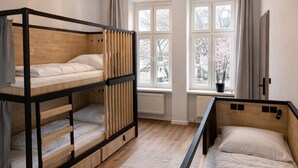 A room with bunk beds, a hanging light fixture, a window with a view of trees, and a radiator. - Privates Dreibettzimmer mit modernem Design (Berlin Sleep Club) (Berlin)