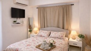 Une chambre à coucher avec un lit, des tables de chevet, une télévision et un ventilateur de plafond.