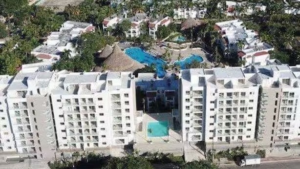 Un hôtel de grande hauteur doté de nombreux balcons, d’une piscine centrale et d’un espace paysager aménagé tout autour.