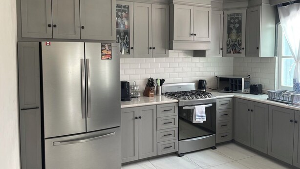 A modern kitchen with grey cabinets, a stainless steel refrigerator, a gas stove, and a microwave. - Beautiful, modern 2-bedroom home located on a private street. (Teoloyucan)