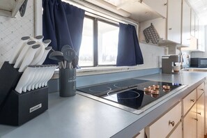 A kitchen with a black induction cooktop, a set of knives, and a coffee maker.