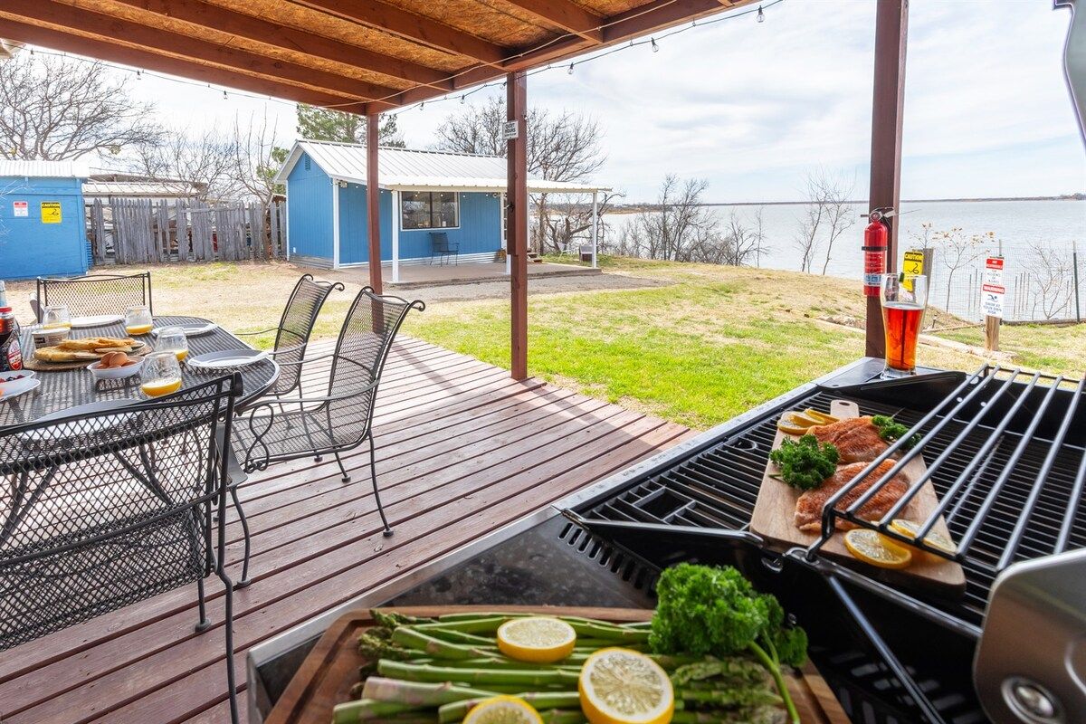 Patio esterno con barbecue, tavolo da pranzo e sedie.